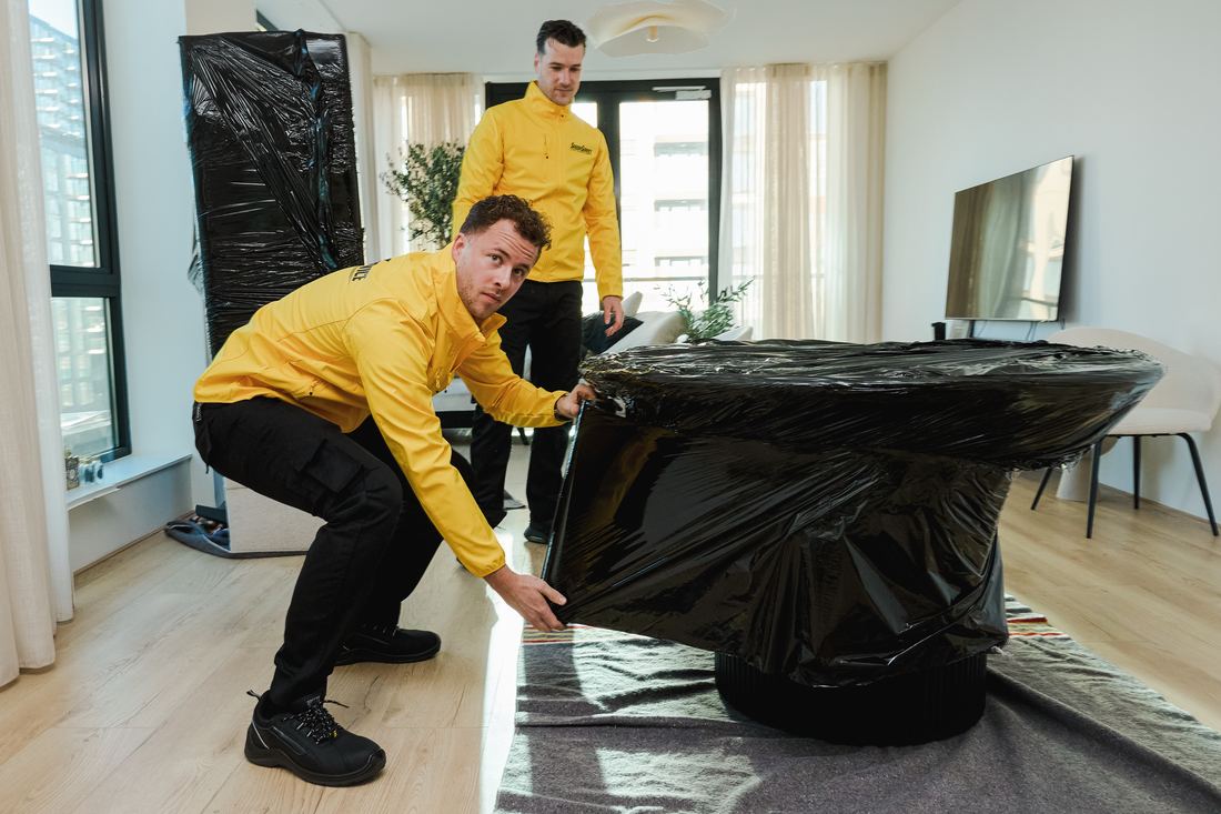 Verhuizers van SpeedyService wikkelen een tafel in beschermfolie op een verhuisdeken